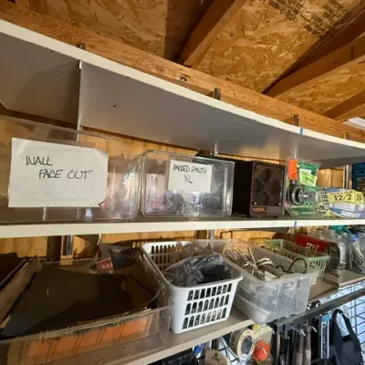 Sale Photo Thumbnail #209: Workshop and storage shelves organized with clear acrylic bins, plastic baskets, electrical wire rolls, and a compact space heater.