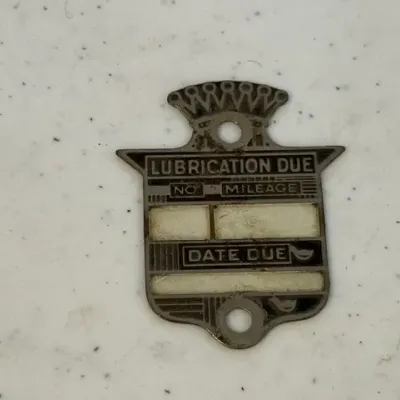 Sale Photo Thumbnail #235: Vintage metal Cadillac-style service tag marked 'Lubrication Due', featuring fields for mileage and date.