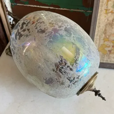 Sale Photo Thumbnail #465: Vintage Hollywood Regency style swag pendant light featuring an iridescent textured glass globe with brass hardware.