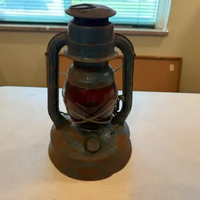Sale Photo Thumbnail #41: Vintage Dietz Monarch railroad lantern featuring a weathered blue metal frame and a deep red glass globe.