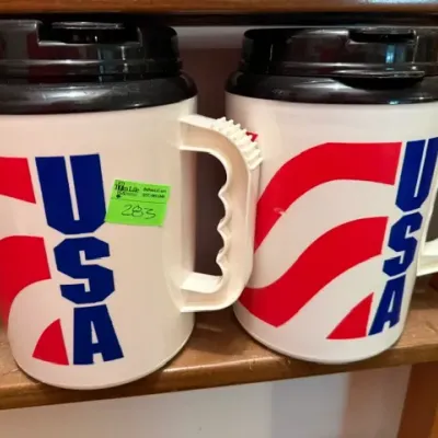 Sale Photo Thumbnail #276: Pair of vintage insulated plastic travel mugs featuring a patriotic USA graphic and black pop-top lids.