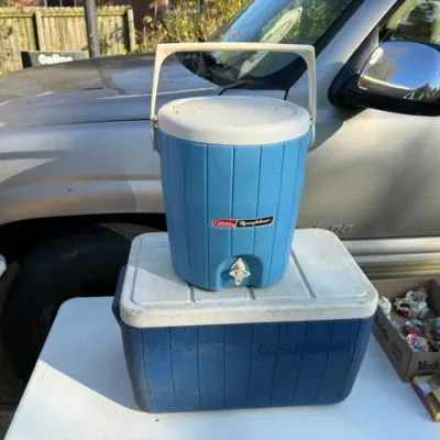 Sale Photo Thumbnail #456: Pair of vintage blue Coleman coolers, including a rectangular ice chest and a round beverage dispenser jug.