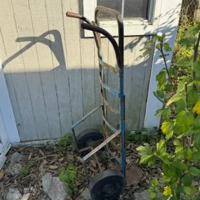 Sale Photo Thumbnail #503: Vintage heavy-duty metal hand truck dolly with blue paint and solid rubber wheels.
