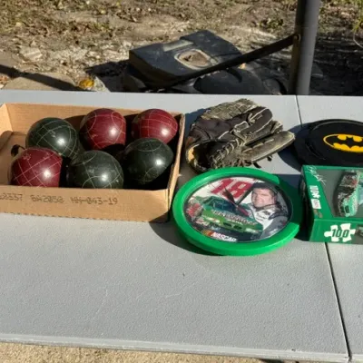 Sale Photo Thumbnail #470: Assorted collection of items including a vintage bocce ball set, a well-worn baseball glove, a Batman frisbee, and Bobby Labonte NASCAR memorabilia.