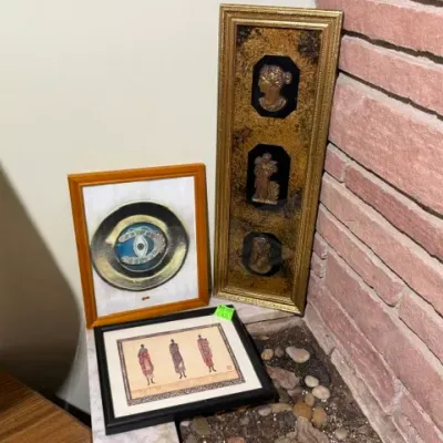 Sale Photo Thumbnail #134: Collection of eclectic framed wall art including an evil eye print, a vertical metallic cameo piece, and an African figure illustration.