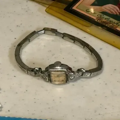 Sale Photo Thumbnail #427: Vintage women's Art Deco style wristwatch with a square dial, silver-tone metal case, and matching expansion band.