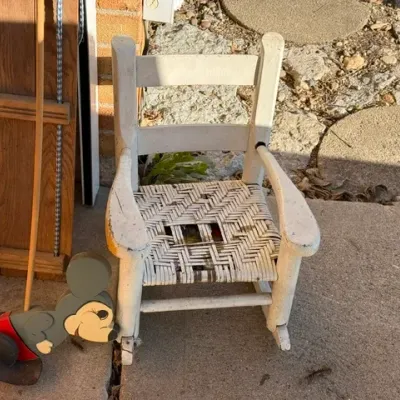Sale Photo Thumbnail #475: Vintage white wooden child's rocking chair with a woven seat showing wear, paired with a vintage Mickey Mouse wooden push toy.