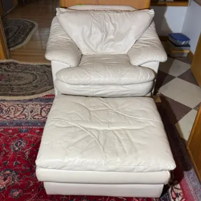 Sale Photo Thumbnail #255: Off-white leather armchair with matching ottoman, featuring plush cushioned upholstery and modern late 20th-century styling.