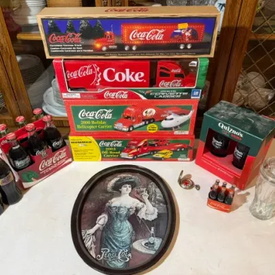 Sale Photo Thumbnail #100: Collection of vintage Coca-Cola memorabilia, including toy trucks in original boxes, glass bottles, a miniature bottle set, and a Pepsi-Cola oval tray.