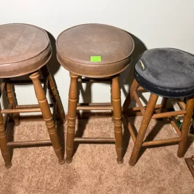 Sale Photo Thumbnail #329: Trio of vintage wooden barstools with round padded vinyl seats, showing age-appropriate wear and surface scuffs.