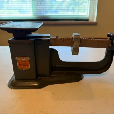 Sale Photo Thumbnail #37: Vintage Triner Air Mail Accuracy postal scale with a dark metal body and sliding weight mechanism.