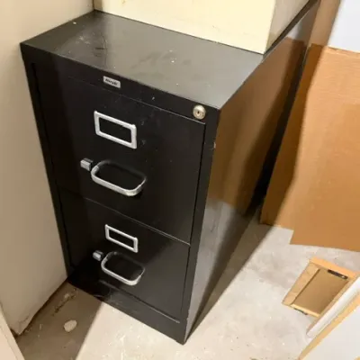 Sale Photo Thumbnail #405: Black Hirsh two-drawer metal filing cabinet with silver handles and a lock mechanism, showing minor surface scuffs.