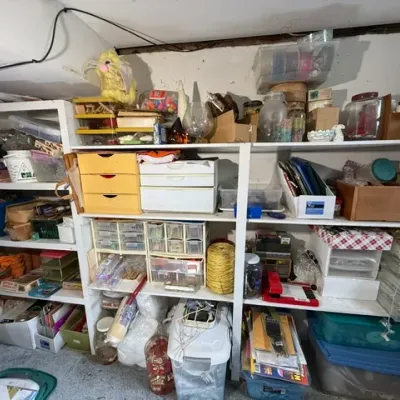 Sale Photo Thumbnail #374: White wooden shelving units filled with various crafting supplies, plastic storage bins, small drawers, and hobby materials.