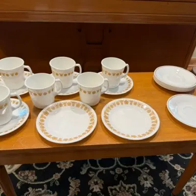 Sale Photo Thumbnail #11: Vintage Corelle Butterfly Gold cups and saucers set arranged on a wooden bench.