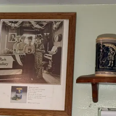 Sale Photo Thumbnail #312: Framed vintage Morton Salt advertisement featuring a black-and-white photograph, paired with a commemorative Morton Salt tin displayed on a wooden shelf.