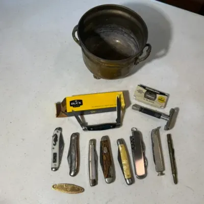 Sale Photo Thumbnail #64: Collection of vintage pocket knives, including a Buck knife in its original box, a safety razor with Gillette blades, and a brass pot.