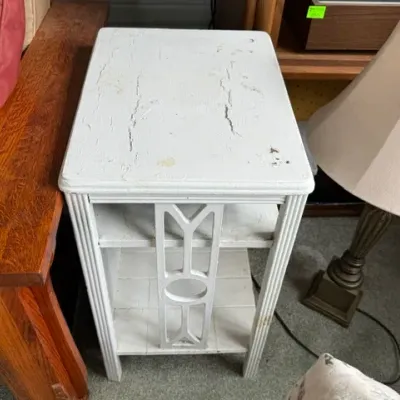 Sale Photo Thumbnail #183: Vintage white-painted wooden side table featuring a lower shelf, fluted legs, decorative side fretwork, and noticeable surface cracking to the paint.