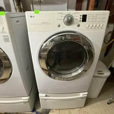 Sale Photo Thumbnail #387: White LG Sensor Dry electric clothes dryer featuring a chrome rimmed front door and a bottom drawer pedestal.