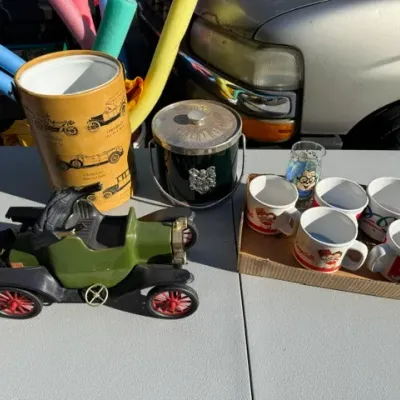 Sale Photo Thumbnail #442: Vintage barware and novelty collection including an antique car-shaped decanter, classic car wastebasket, ice bucket, and a set of Campbell's Soup and novelty mugs.