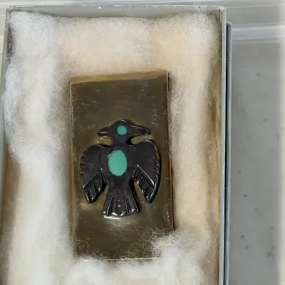 Sale Photo Thumbnail #231: Vintage brass money clip featuring a Southwestern-style thunderbird motif with turquoise inlay accents, presented in a gift box.