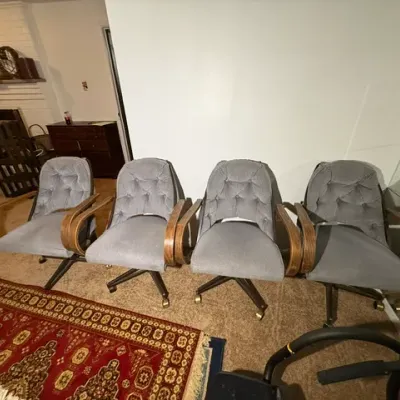 Sale Photo Thumbnail #347: Set of four mid-century modern rolling armchairs featuring grey tufted velvet upholstery, bentwood armrests, and brass casters.