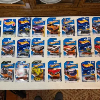 Sale Photo Thumbnail #77: Collection of 24 carded Hot Wheels die-cast toy vehicles displayed in three rows, including muscle cars, hot rods, and a motorcycle.