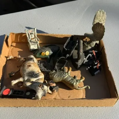 Sale Photo Thumbnail #451: Cardboard flat filled with vintage cast iron and metal miniatures, including a cow figure, mini irons, an eagle, and a dollhouse chair.