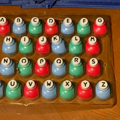 Sale Photo Thumbnail #366: Complete 26-piece set of colorful alphabet paper craft punches in a clear plastic storage tray.