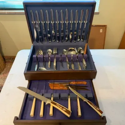 Sale Photo Thumbnail #36: Vintage flatware service set in a wooden storage chest with blue felt lining, including knives, forks, spoons, and carved-handle serving utensils.