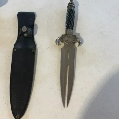 Sale Photo Thumbnail #218: Ornate split-blade fantasy dagger with a spiraled black handle and decorative guard, shown alongside a black faux-leather sheath.