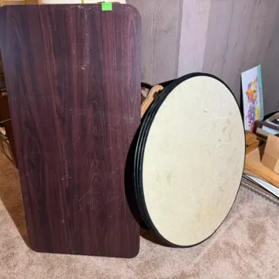 Sale Photo Thumbnail #338: Two disassembled table tops, including a rectangular dark faux-wood finish surface and a round cream-colored laminate top.