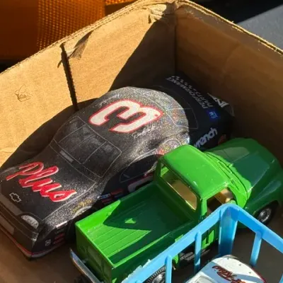 Sale Photo Thumbnail #449: Collection of toy vehicles in a box, including a Dale Earnhardt #3 GM Goodwrench Chevrolet stock car bank and a green pickup truck.
