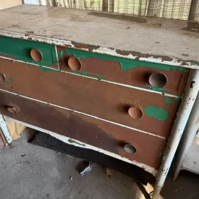 Sale Photo Thumbnail #463: Vintage painted wooden dresser featuring four drawers with wooden knobs, showing significant wear, distressing, and peeling paint layers.