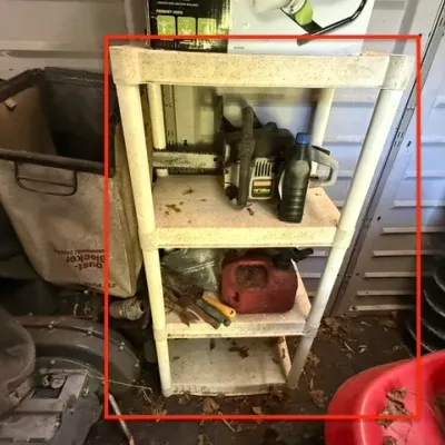 Sale Photo Thumbnail #282: Four-tier off-white plastic shelving unit loaded with yard equipment, including a gas-powered chainsaw and a small red fuel container.