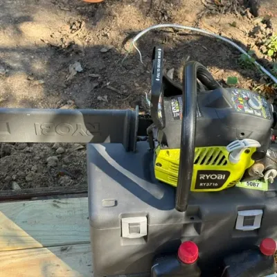 Sale Photo Thumbnail #202: Ryobi RY3716 gas-powered chainsaw with scabbard, set atop its hard carrying case.