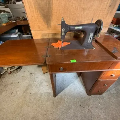 Sale Photo Thumbnail #365: Vintage electric sewing machine built into a wooden drop-leaf cabinet with side drawers.