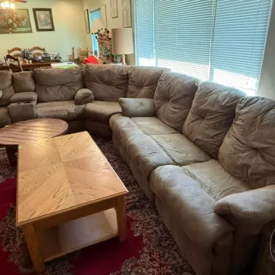 Sale Photo Thumbnail #43: Large brown microfiber sectional sofa with tufted cushions, paired with light-finish wooden coffee tables over a patterned red area rug.