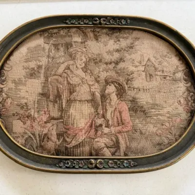 Sale Photo Thumbnail #187: Vintage oval framed woven tapestry picture featuring a coursing scene of a man and woman in an ornate brass frame with floral details.
