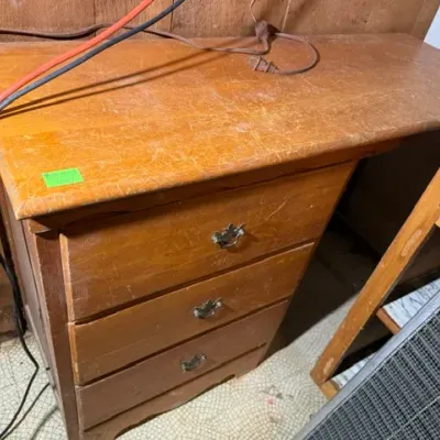 Sale Photo Thumbnail #398: Vintage light wood desk featuring three stacked drawers with metal batwing bail handles, showing heavy surface scratches and wear.