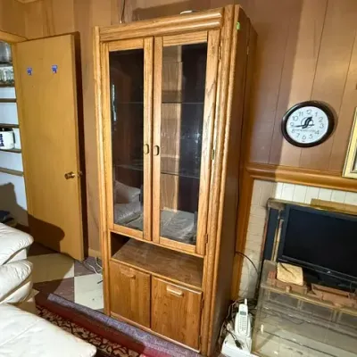 Sale Photo Thumbnail #256: Tall vintage oak display cabinet featuring glass upper doors, interior shelves, and a bottom storage compartment with wooden doors.