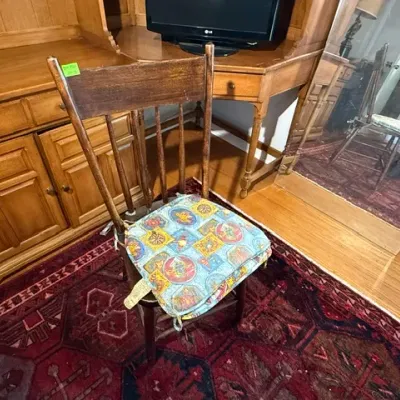 Sale Photo Thumbnail #291: Vintage wooden spindle-back dining chair featuring a top rail crest and a colorful patterned seat cushion.