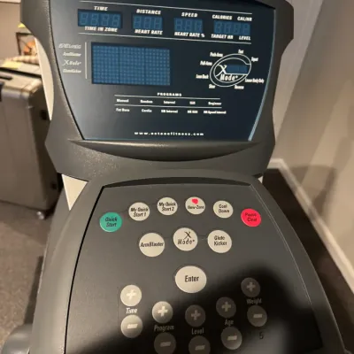 Sale Photo Thumbnail #51: Control console of an Octane Fitness Q37e elliptical machine, featuring a digital display and various preset workout program buttons.