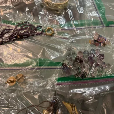 Sale Photo Thumbnail #9: Collection of assorted jewelry pieces stored in clear plastic bags, including beaded necklaces, loose polished stones, a gold-tone cuff, and various charms.
