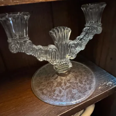 Sale Photo Thumbnail #22: Vintage clear pressed glass double candelabra featuring a detailed floral pattern on the circular base.