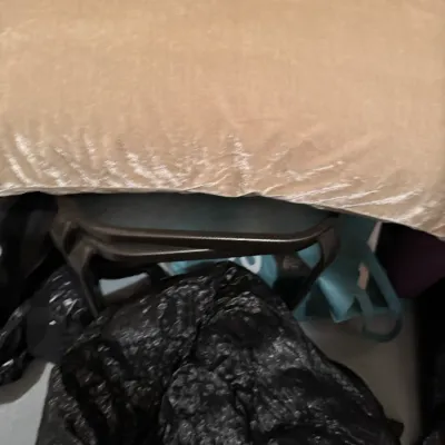 Sale Photo Thumbnail #60: Tan velvet bolster pillow resting on top of a small side table.