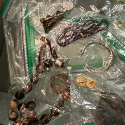 Sale Photo Thumbnail #11: Assorted jewelry pieces individually packaged in plastic bags, including beaded necklaces, a silver-tone twisted cuff bracelet, cufflinks, and pendants.