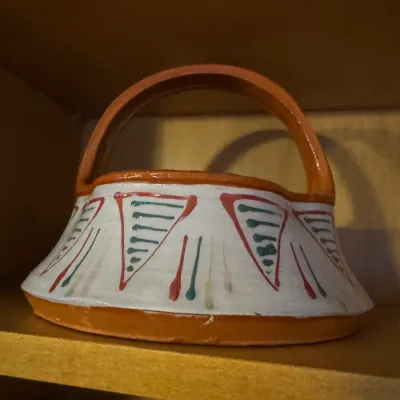 Sale Photo Thumbnail #23: Hand-painted terracotta pottery basket with a flared rim and arched handle, decorated in red, green, and white folk art motifs.