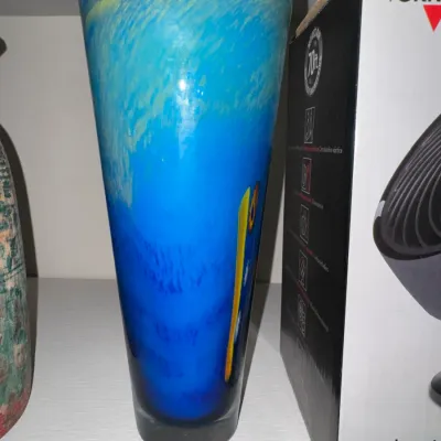 Sale Photo Thumbnail #43: Tall blue and yellow swirl art glass vase with a flared rim, displayed next to a boxed Vornado fan.