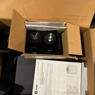 Sale Photo Thumbnail #37: Cardboard box containing electronics, including a pair of black Samsung speakers, instruction manuals, and associated cabling.