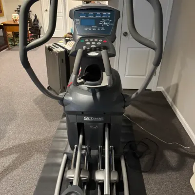 Sale Photo Thumbnail #50: Octane Fitness Q37e elliptical machine resting on a black floor mat, featuring multi-grip handlebars and a digital console.